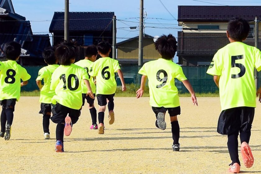 サッカー教室で走る子供達の背中